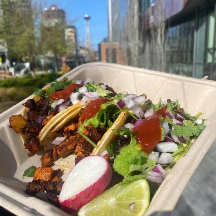 Barriga Llena tacos topped with salsa roja, onion, cilantro, radish, and lime